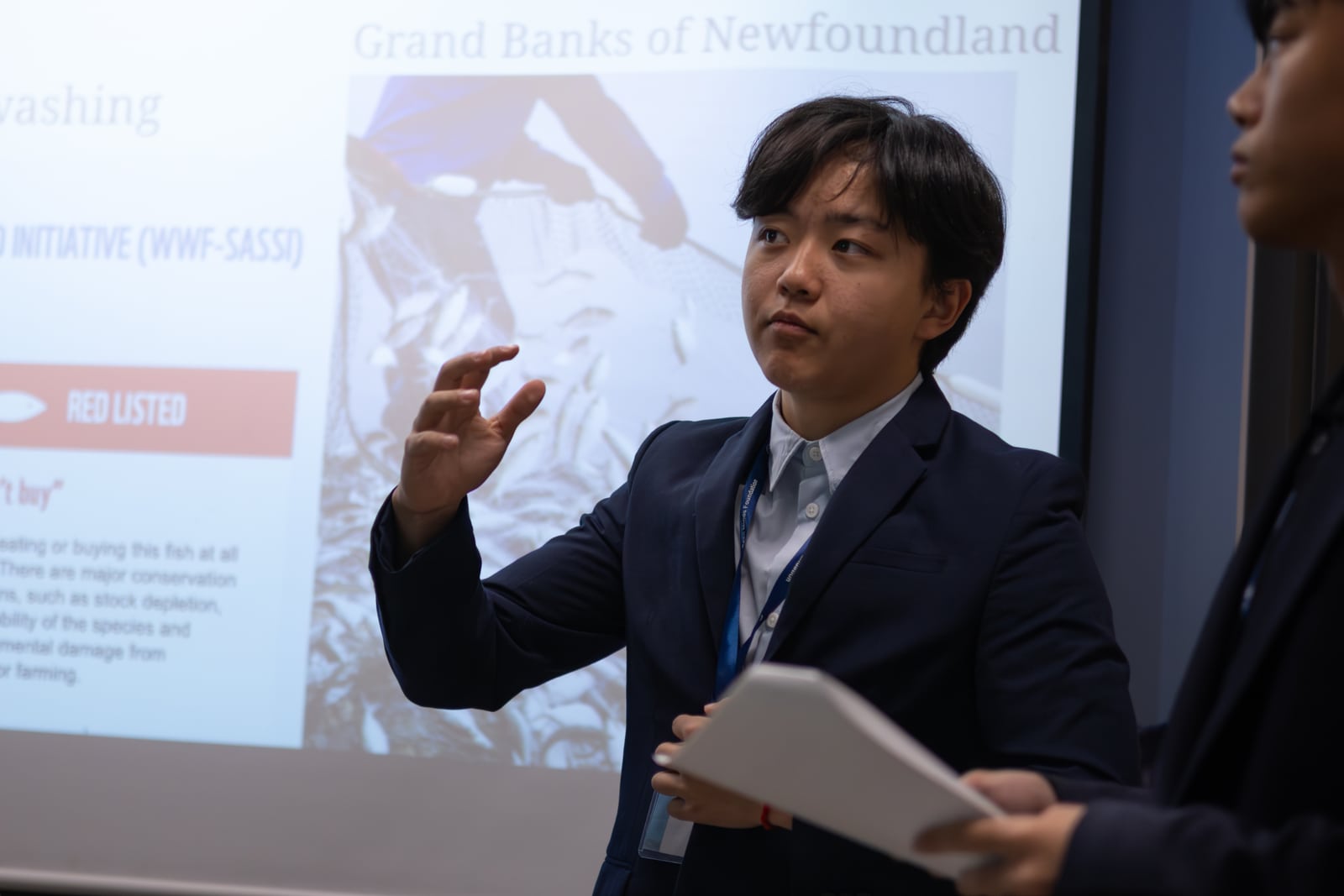 A student presenting his team’s recommendation, notes in hand