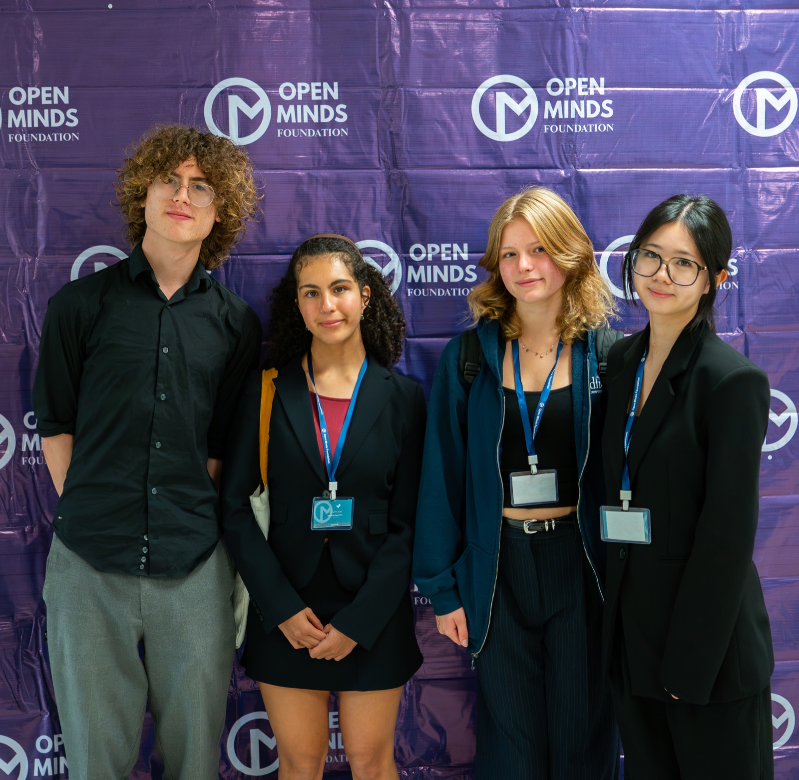 Four Velocity attendees in front of the Open Minds Foundation backdrop
