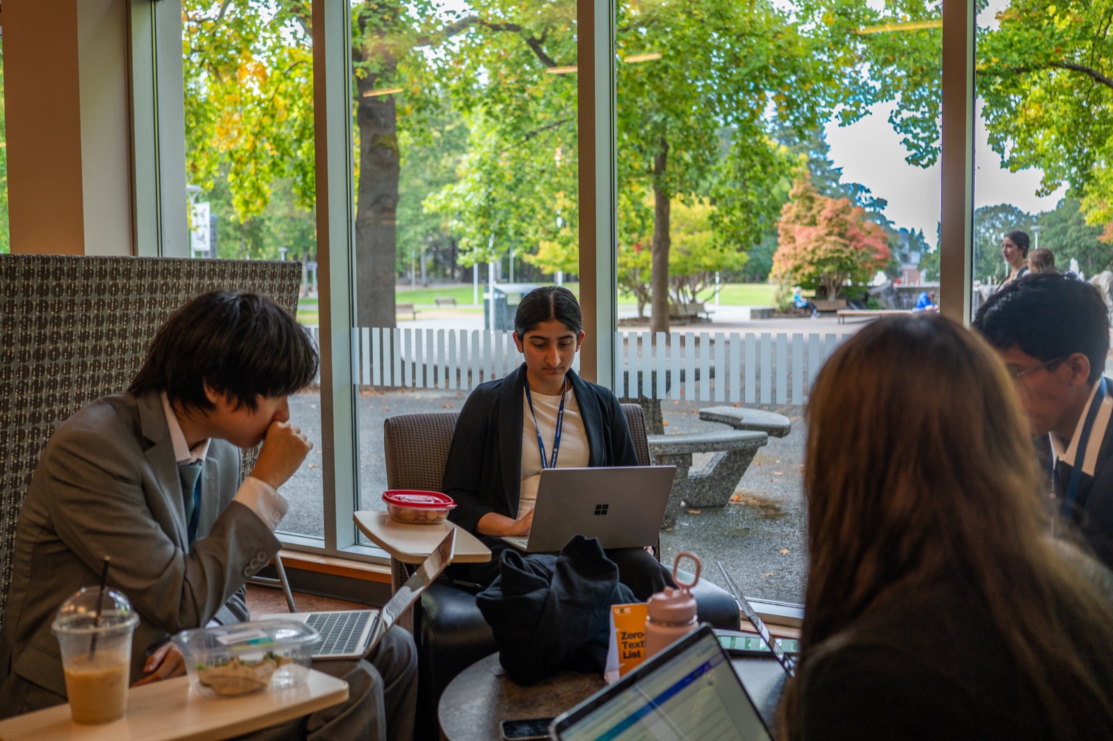 Two teams working at tables by a window on campus